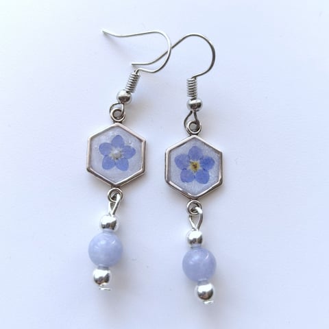 Pair of silver hexagonal earrings with pressed blue flowers and lavender beads hanging from surgical steel hooks